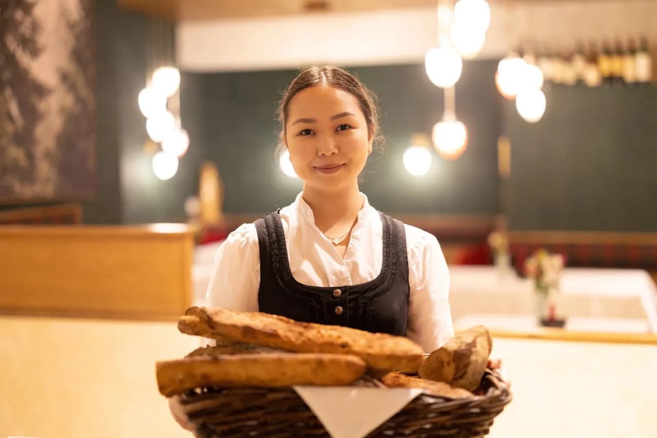 Mitarbeiterin im Dirndl mit einem Korb frisch gebackenem Brot
